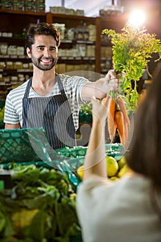 Smiling male staff assisting a woman with grocery shopping