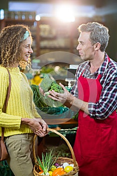 Smiling male staff assisting a woman with grocery shopping