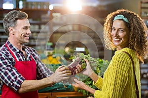 Smiling male staff assisting a woman with grocery shopping