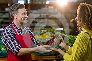 Smiling male staff assisting a woman with grocery shopping