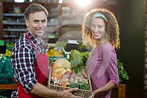 Smiling male staff assisting a woman with grocery shopping