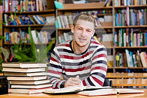 Smiling male student with open book working in a library