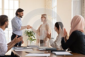 Smiling male team leader shaking hands with mature colleague.