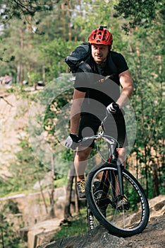 smiling male trial biker in protective helmet riding on mountain bicycle