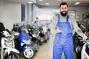 Smiling male worker demonstrating motorcycles