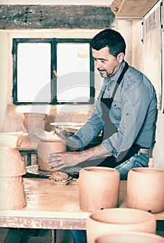 Smiling male working with clay on pottery wheel