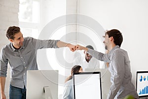 Smiling males giving fist bumps excited by shared goal achieveme