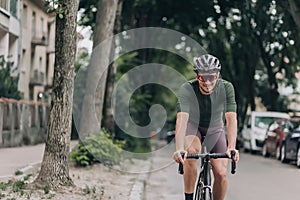 Smiling man in activewear riding black bike on city street