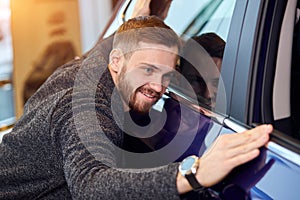 Smiling man adores his new modern luxury car. love at first sight photo