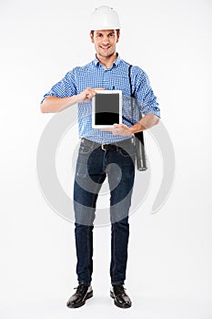 Smiling man architect in building helmet holding blank screen tablet