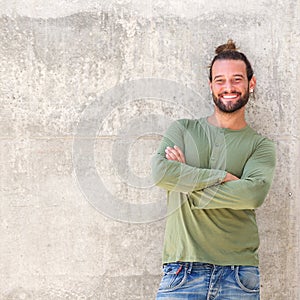 Smiling man with arms crossed leaning against wall