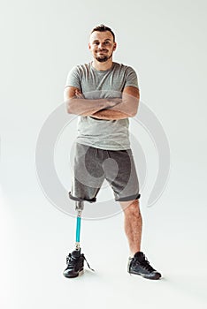 smiling man with arms crossed and leg prosthesis looking at camera