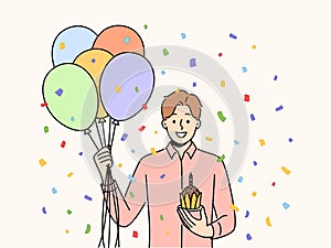 Smiling man with balloons and cupcake greeting with birthday