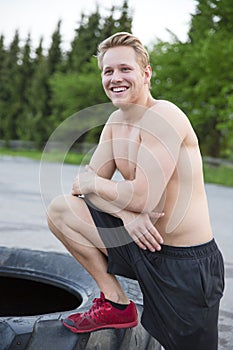 Smiling man with bare upper body rests outdoor