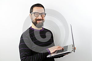 Man with beard and glasses isolated on white background using laptop looking at camera photo