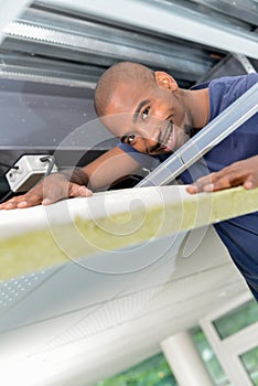 Smiling man bent over insulation in roofspace