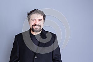 Smiling man in black jacket over gray background