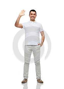 Smiling man in blank white t-shirt waving hand