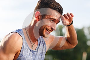Smiling man in blue t-shirt wiping sweat on nature