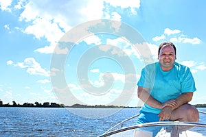 Smiling man in a boat on a background of smooth water of a blue cloudy sky