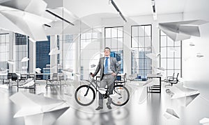 Smiling man in business suit standing with bike