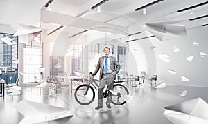 Smiling man in business suit standing with bike