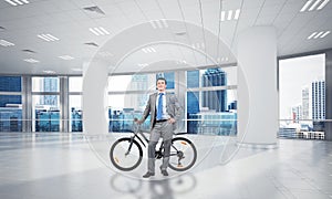 Smiling man in business suit standing with bike