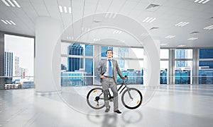 Smiling man in business suit standing with bike