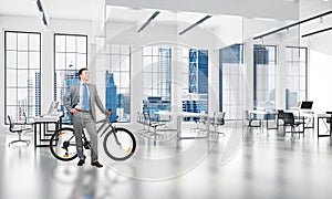 Smiling man in business suit standing with bike