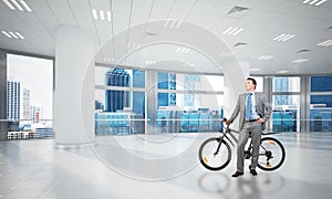 Smiling man in business suit standing with bike