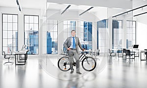 Smiling man in business suit standing with bike