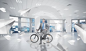 Smiling man in business suit standing with bike