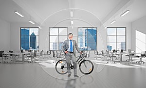 Smiling man in business suit standing with bike