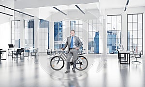 Smiling man in business suit standing with bike