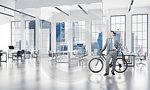 Smiling man in business suit standing with bike