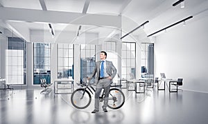 Smiling man in business suit standing with bike