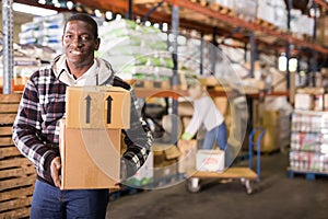 Smiling man carrying boxes in warehouse