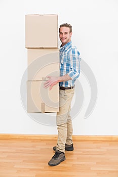 Smiling man carrying pile of cardboard moving boxes