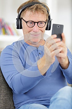 smiling man with cell phone and headphones at home