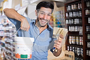 Smiling man choosing brushes and varnishes