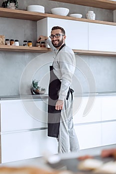 Smiling man choosing spices in the kitchen