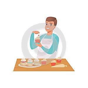 Smiling man cooking cupcakes, young man in casual clothing and apron preparing healthy meal in kitchen vector