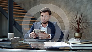 Smiling man counting money at workplace in slow motion. Guy made easy money.