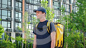 Smiling man courier food delivery with backpack turns head and looks camera