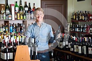 Smiling man customer buying bottle of wine