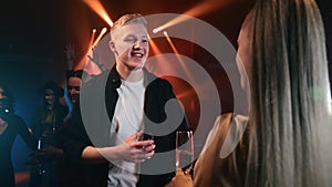 Smiling man dancing with blonde woman disco night club party crowded dance floor leisure discotheque