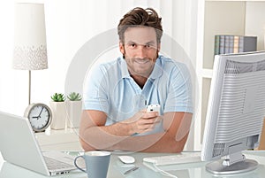 Smiling man at desk with mobile phone