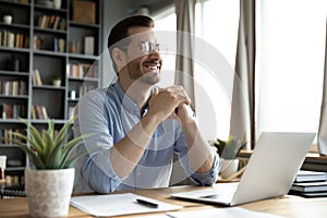 Smiling man distracted form laptop dreaming of success