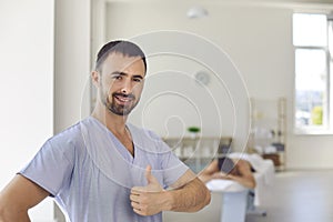Smiling man doctor chiropractor or masseur showing thumbs up sign