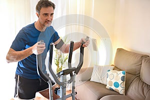 Man doing elliptical bike at home listening to music detail photo